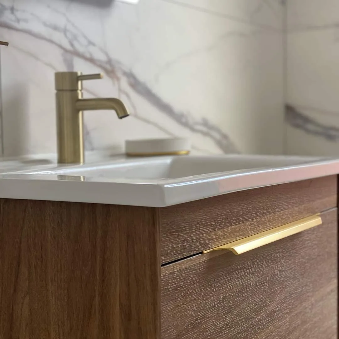 Brass basin tap and wooden vanity unit close up